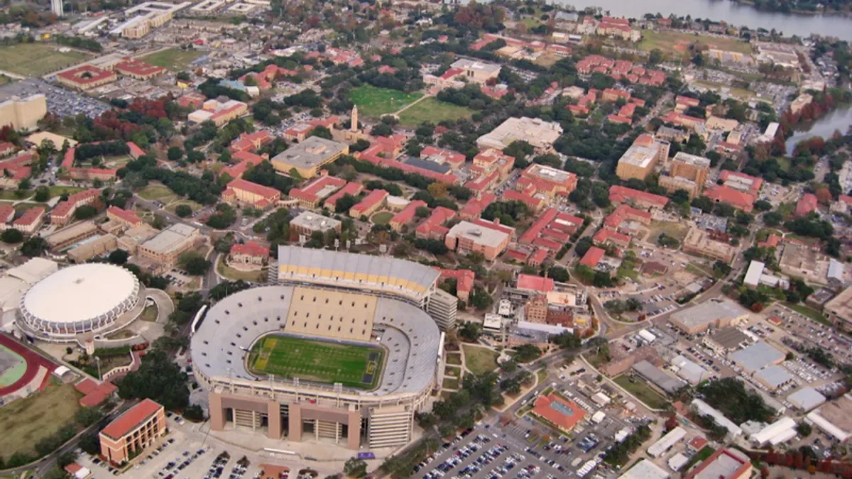 Aerial view of campus including football stadium and red-roofed buildings.